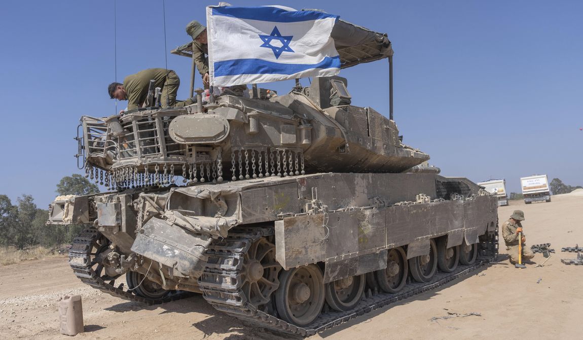An Israeli soldier attaches an Israeli flag on top of an armoured personnel carriers (APC) near Israel&#x27;s border with Gaza, in southern Israel, Monday, April 15, 2024. (AP Photo/Ohad Zwigenberg)