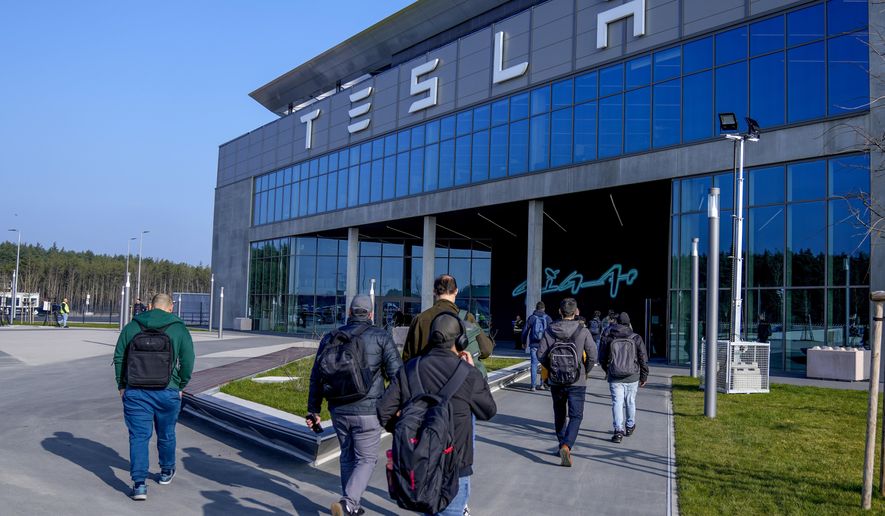 People walk to the Tesla Gigafactory for electric cars in Gruenheide near Berlin, Germany,March 13, 2024. After reporting dismal first-quarter sales, Tesla is planning to lay off about a tenth of its workforce as it tries to cut costs, multiple media outlets reported Monday. (AP Photo/Ebrahim Noroozi, File)