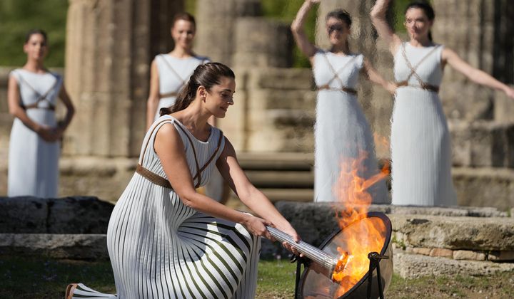 Greek actress Xanthi Georgiou, playing the role of the High Priestess, lights the torch during the lighting of the Olympic flame at Ancient Olympia site, birthplace of the ancient Olympics in southwestern Greece Oct. 18, 2021. On Tuesday, April 16, 2024, the flame for this summer&#x27;s Paris Olympics will be lit and be carried through Greece for more than 5,000 kilometers (3,100 miles) before being handed over to French organizers at the Athens site of the first modern Olympics. (AP Photo/Thanassis Stavrakis, File)