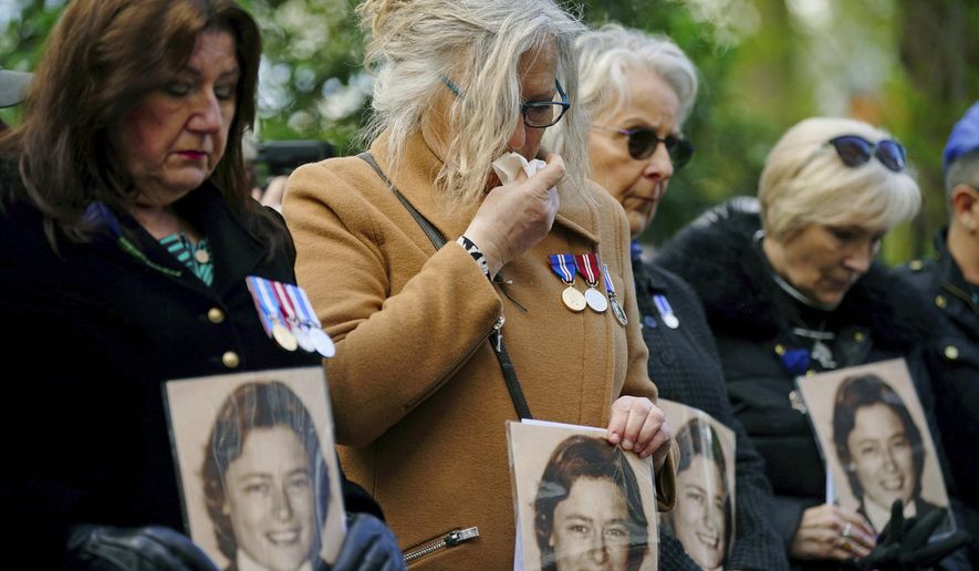 Colleagues of police constable Yvonne Fletcher hold photos of her as they gather in St James&#x27;s Square for a 40th anniversary memorial service, in London, Wednesday, April 17, 2024. Hundreds of people attended a vigil in central London to commemorate the life of a police officer who was shot dead 40 years ago from inside the Libyan embassy. Constable Yvonne Fletcher, 25, was killed when men armed with submachine guns fired from the embassy’s windows, while she was policing a demonstration outside the building against the regime of then-Libyan leader Moammar Gadhafi. (Victoria Jones/PA via AP)