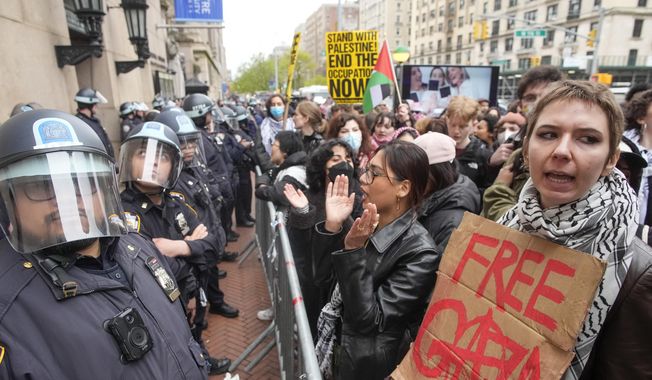 Police in riot gear stand guard as demonstrators chant slogans outside the Columbia University campus, Thursday, April 18, 2024, in New York. The protesters were calling for the school to divest from corporations they claim profit from the war in the Middle East. (AP Photo/Mary Altaffer)