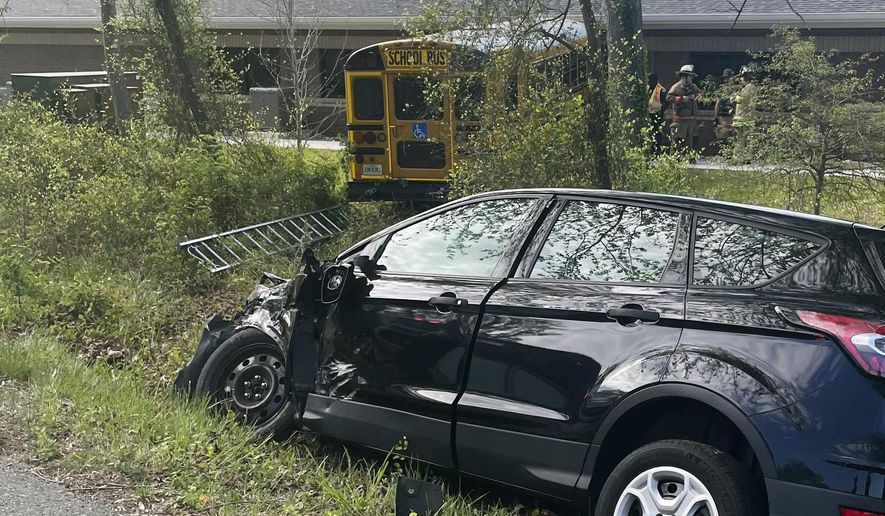 This image provided by the Fairfax County Fire and Rescue show the scene of a school bus crash, Thursday, April 18, 2024, in Fairfax County, Va. Two students and a school bus driver were injured Thursday morning when the bus and small car swerved to avoid each other and the bus struck a Virginia Department of Motor Vehicles building, officials said. (Fairfax County Fire and Rescue via AP)