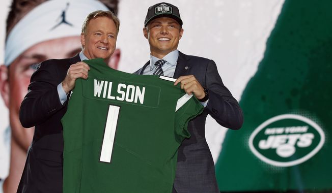 BYU quarterback Zach Wilson holds a New York Jets jersey with NFL commissioner Roger Goodell after being selected second overall by the team in the first round of the NFL football draft, Thursday, April 29, 2021, in Cleveland. Teams are using premium draft picks on quarterbacks at an increasingly high rate. Still, the league-wide hit rate remains largely a tossup. (AP Photo/Jeff Haynes, File)