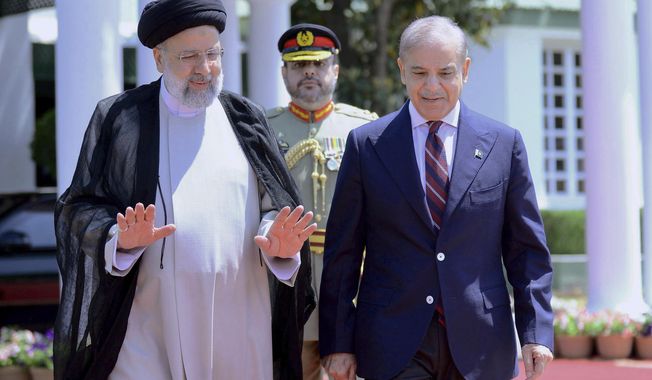 In this photo released by Prime Minister Office, Iranian President Ebrahim Raisi, left, walks with Pakistan&#x27;s Prime Minister Shehbaz Sharif during a welcome ceremony in the prime minister house in Islamabad, Pakistan, Monday, April 22, 2024. (Prime Minister Office via AP)