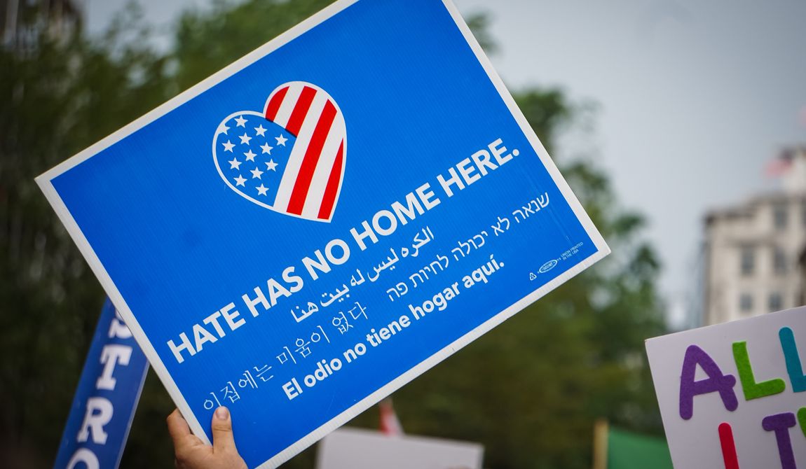 An activist in DC holds a protest sign that says &quot;Hate has no home here&quot; at the Unite the Right 2 counter-protest. WASHINGTON, DC - AUGUST 13, 2018. File photo credit: Stephanie Kenner via Shutterstock.