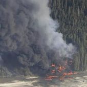 A fire burns after a Douglas C-54 Skymaster crashed into the Tanana River outside Fairbanks, Alaska, Tuesday, April 23, 2024. (Michaela Matherne via AP)