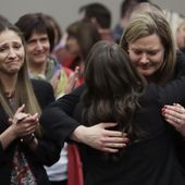 FILE -In this Jan. 24, 2018, file photo, victims react and hug Assistant Attorney General Angela Povilaitis after Larry Nassar was sentenced by Judge Rosemarie Aquilina to 40 to 175 years in prison during a sentencing hearing in Lansing, Mich. The U.S. Justice Department announced a $138.7 million settlement Tuesday, April 23, 2024, with more than 100 people who accused the FBI of grossly mishandling allegations of sexual assault against Larry Nassar in 2015 and 2016, a critical time gap that allowed the sports doctor to continue to prey on victims before his arrest. (AP Photo/Carlos Osorio, File)