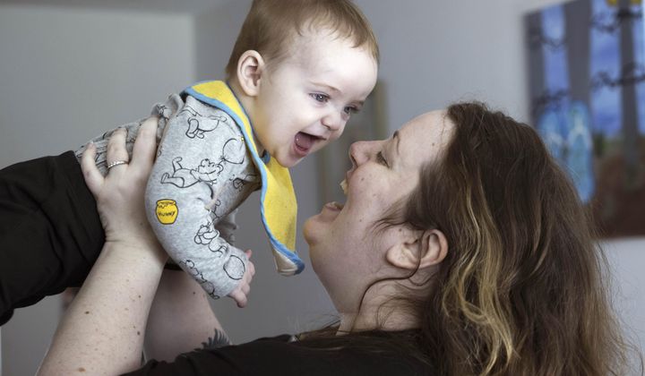 Nicole Slemp, a new mother of seven-month-old William, lifts up her son in their home, Thursday, March 14, 2024 in Auburn, Wash. (Ellen M. Banner/The Seattle Times via AP)