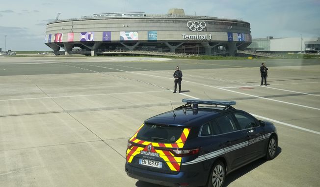 Gendarmes pose in front of the Charles de Gaulle airport, terminal 1, where the olympic rings were installed, in Roissy-en-France, north of Paris, Tuesday, April 23, 2024 in Paris. (AP Photo/Thibault Camus)