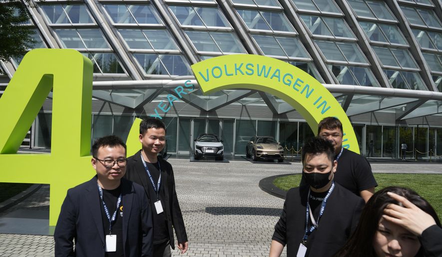 Workers stand near a sign marking Volkswagen&#x27;s 40 years (in China) in Beijing, Wednesday, April 24, 2024. Foreign automakers have been caught flat-footed in China by an electric vehicle boom that has shaken up the market over the last three years. That has left manufacturers like Volkswagen scrambling to develop new models for a very different market than at home. (AP Photo/Ng Han Guan)