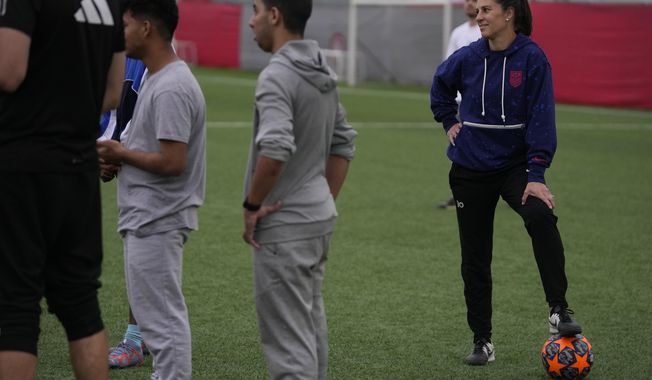 The two-time FIFA Player of the Year Carli Lloyd watches the training of young migrants at Olympiacos Training Center in Athens, Monday, April 22, 2024. Elite American athletes and coaches, including the former US soccer players Carli Lloyd and Cobi Jones, take part in the 2024 spring roster of U.S. Soccer Sports Envoys organized by the U.S. Department of State. (AP Photo/Thanassis Stavrakis)