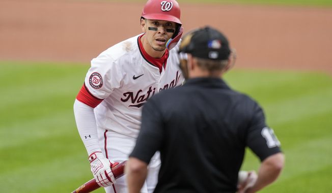 Washington Nationals designated hitter Joey Meneses discusses a call with home plate umpire Brian Walsh during the first inning of a baseball game against the Los Angeles Dodgers at Nationals Park, Thursday, April 25, 2024, in Washington. (AP Photo/Alex Brandon)
