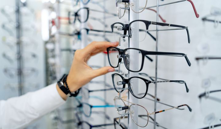 A woman examines eyeglass frames at an optician’s store. (Image by Shutterstock/Terelyuk) ** FILE **