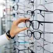 A woman examines eyeglass frames at an optician’s store. (Image by Shutterstock/Terelyuk) ** FILE **
