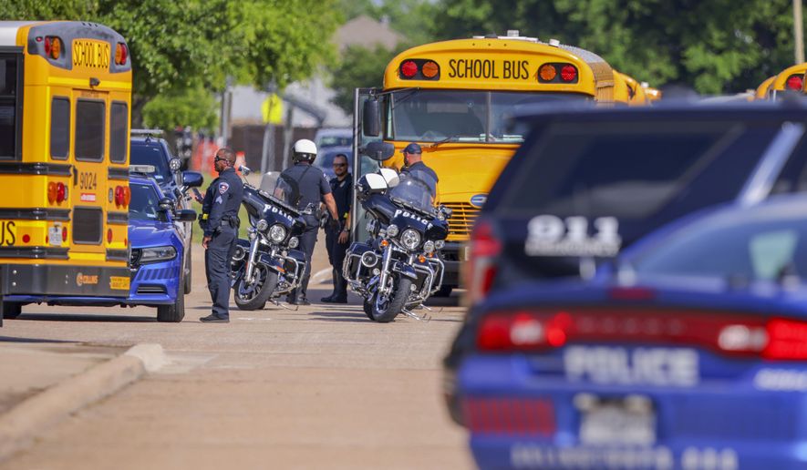 Police officers prepare to escort students to be reunited with their families at Arlington Bowie High School after the school was placed on a lockdown due to a suspected shooting outside the school building, Wednesday April 24, 2024, in Arlington, Texas. (AP Photo/Gareth Patterson)