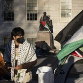 A student protester stands in front of the statue of John Harvard, the first major benefactor of Harvard College, draped in the Palestinian flag, at an encampment of students protesting against the war in Gaza, at Harvard University in Cambridge, Mass., on Thursday, April 25, 2024. (AP Photo/Ben Curtis) ** FILE **