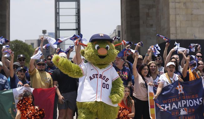 Houston Astros team mascot Orbit and fans, pose for a photo backdropped by the Monument to the Revolution in Mexico City, Thursday, April 25, 2024. The Houston Astros will face Colorado Rockies in two regular season game beginning Saturday, at Mexico City&#x27;s Alfredo Harp Helú stadium. (AP Photo/Fernando Llano)