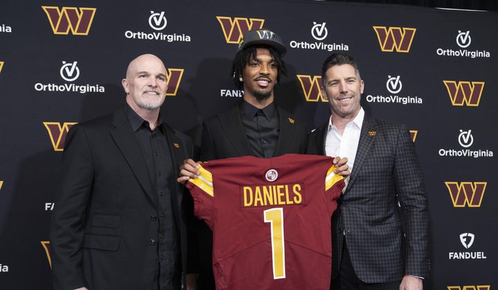 Washington Commanders&#x27; first round draft pick Jayden Daniels holds his Commanders jersey with head coach Dan Quinn, left, and general manager Adam Peters, right, following an NFL football news conference in Ashburn, Va., Friday, April 26, 2024. (AP Photo/Manuel Balce Ceneta)