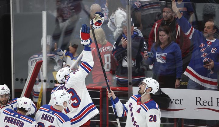 New York Rangers left wing Chris Kreider (20) holds his glove on a stick to high-five teammate Matt Rempe after defeating the Washington Capitals in Game 3 of an NHL hockey Stanley Cup first-round playoff series, Friday, April 26, 2024, in Washington. (AP Photo/Tom Brenner)