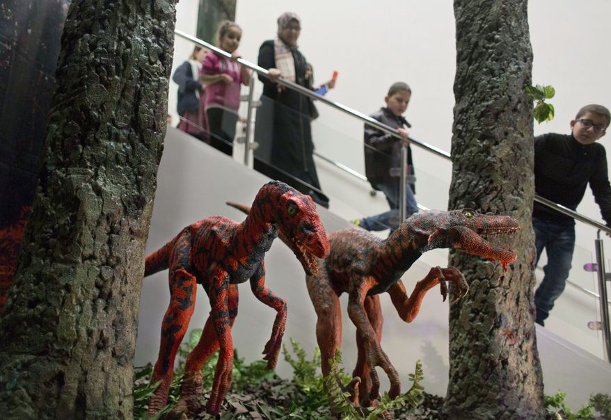 Visitors look at models of the Velociraptor Dinosaurs during the opening ceremony of the Baby Dinosaurs and Giant Insect Exhibition, in the West Bank city of Bethlehem, Tuesday, March 14, 2017. The exhibition was donated by the Bethlehem-Bath Links charity, based in the British city of Bath, in an effort to help create the first Palestinian children's natural history museum. (AP Photo/Nasser Nasser) **FILE**