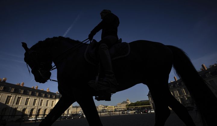 A horsewoman trains with her horse in the main courtyard of the royal stables, in Versailles, Thursday, April 25, 2024. More than 340 years after the royal stables were built under the reign of France&#x27;s Sun King, riders and horses continue to train and perform in front of the Versailles Palace. The site will soon keep on with the tradition by hosting the equestrian sports during the Paris Olympics. Commissioned by King Louis XIV, the stables have been built from 1679 to 1682 opposite to the palace&#x27;s main entrance. (AP Photo/Aurelien Morissard)