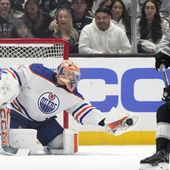 Edmonton Oilers goaltender Stuart Skinner, left, makes a glove save as Los Angeles Kings center Phillip Danault watches during the first period in Game 4 of an NHL hockey Stanley Cup first-round playoff series Sunday, April 28, 2024, in Los Angeles. (AP Photo/Mark J. Terrill)