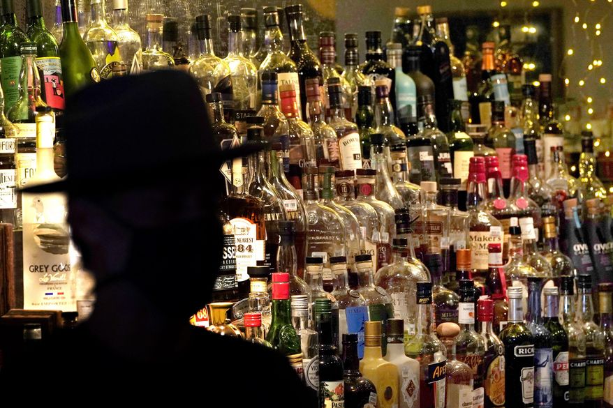 Bottles of alcohol sit on shelves at a bar in Houston on June 23, 2020. Moderate drinking was once thought to have benefits for the heart, but better research methods starting in the 2010s have thrown cold water on that. (AP Photo/David J. Phillip) **FILE**