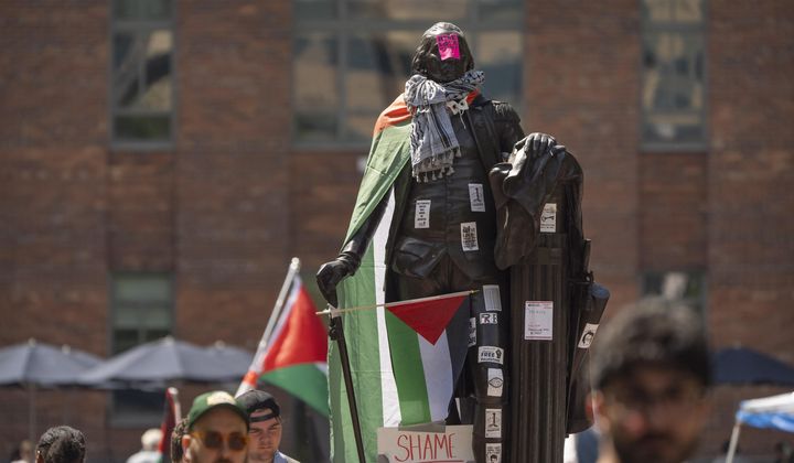 Stickers and Palestininan flags cover a statue of George Washington at an encampment by students protesting against the Israel-Hamas war at George Washington University on Tuesday, April 30, 2024, in Washington. (AP Photo/Mark Schiefelbein)