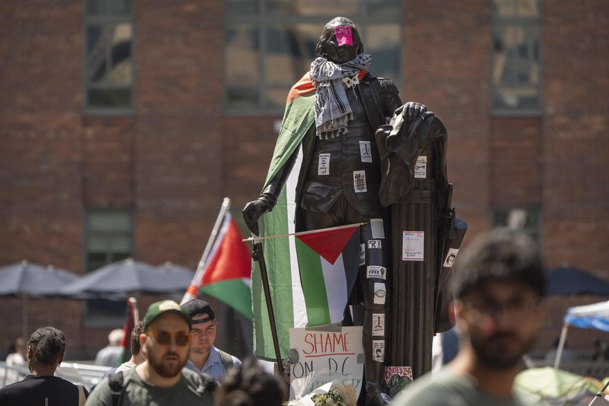 Stickers and Palestininan flags cover a statue of George Washington at an encampment by students protesting against the Israel-Hamas war at George Washington University on Tuesday, April 30, 2024, in Washington. (AP Photo/Mark Schiefelbein)