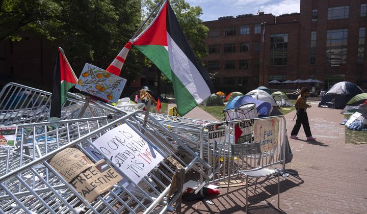 A person walks past a pile of barricades at an encampment by students protesting against the Israel-Hamas war at George Washington University on Tuesday, April 30, 2024, in Washington. (AP Photo/Mark Schiefelbein)