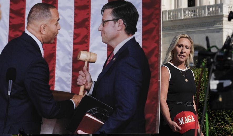 Rep. Marjorie Taylor Greene, R-Ga., walks past a chart showing Minority Leader Hakeem Jeffries, D-N.Y., handing the gavel to Speaker of the House Mike Johnson, R-La., after his election, just before a news conference at the Capitol in Washington, Wednesday, May 1, 2024. (AP Photo/J. Scott Applewhite) **FILE**