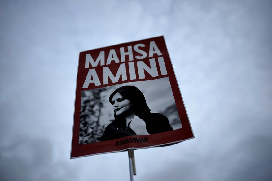 FILE - A woman holds a placard with a picture of Iranian woman Mahsa Amini during a protest against her death, in Berlin, Germany, on Sept. 28, 2022. Iranian prosecutors filed criminal charges Wednesday, May 1, 2024, targeting activists and journalists following a BBC report that alleged security forces "sexually assaulted and killed" a 16-year-old girl who led protests over the death of Mahsa Amini in 2022. (AP Photo/Markus Schreiber, File)