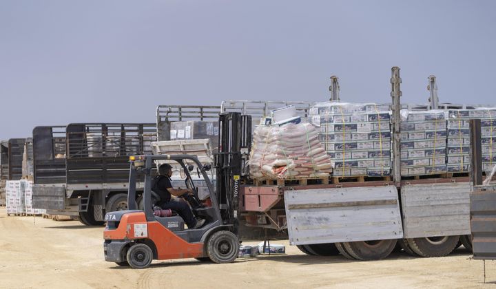 A worker moves a pallet in an inspection area for trucks carrying humanitarian aid supplies bound for the Gaza Strip, on the Palestinian side of the Erez crossing between southern Israel and Gaza, Wednesday, May 1, 2024. (AP Photo/Ohad Zwigenberg)