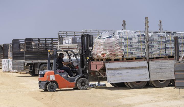 A worker moves a pallet in an inspection area for trucks carrying humanitarian aid supplies bound for the Gaza Strip, on the Palestinian side of the Erez crossing between southern Israel and Gaza, Wednesday, May 1, 2024. (AP Photo/Ohad Zwigenberg)