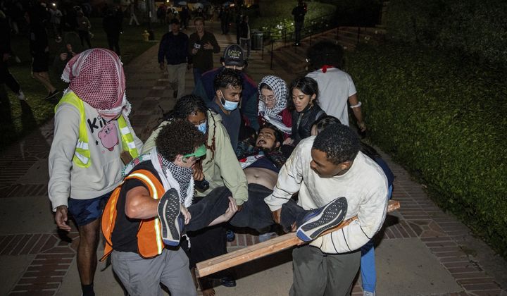 A person is carried away as counter-demonstrators confront a pro-Palestinian encampment at UCLA Tuesday, April 30, 2024, in Los Angeles. Violence erupted as protests sweep across college campuses in America. (AP Photo/Ethan Swope)