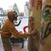 A demonstrator sprays graffiti on a building on the UCLA campus, Wednesday, May 1, 2024, in Los Angeles. (AP Photo/Ethan Swope)