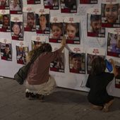 A woman touches photos of Israelis missing and held captive in Gaza that are displayed on a wall in Tel Aviv, Israel, Oct. 21, 2023. Israel and Hamas appear to be seriously negotiating an end to the war in Gaza and the return of Israeli hostages. A leaked truce proposal hints at concessions by both sides following months of stalemated talks. (AP Photo/Petros Giannakouris, File)