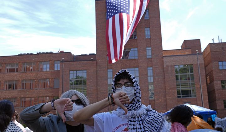 Protesters react as a giant American flag is unfurled on Lisner Hall on the campus of George Washington University in Washington, Friday, May 3, 2024, as demonstrators protest the Israel-Hamas war. (AP Photo/Susan Walsh)