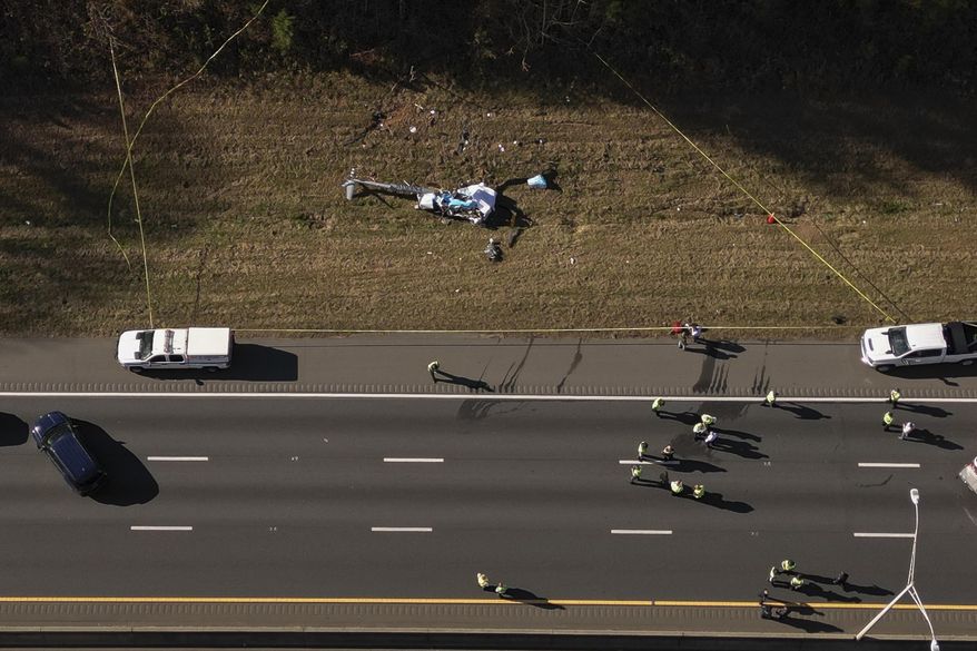 In this image taken with a drone, emergency personnel work at the scene of a helicopter crash on the side of Interstate 77 South in Charlotte, N.C., Nov. 22, 2022. Investigators found disconnected and missing hardware aboard the helicopter that crashed in 2022, killing the pilot and a North Carolina television station’s meteorologist, according to the National Transportation Safety Board's final report on the crash, which was released Thursday, May 2, 2024. (Alex Slitz/The Charlotte Observer via AP, File)