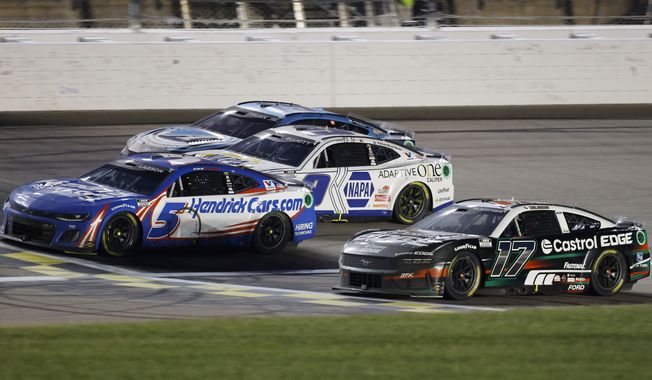 Kyle Larson (5) crosses the finish line milliseconds in front of Chris Buescher (17) for the win during a NASCAR Cup Series auto race at Kansas Speedway in Kansas City, Kan., Sunday, May 5, 2024. (AP Photo/Colin E. Braley)