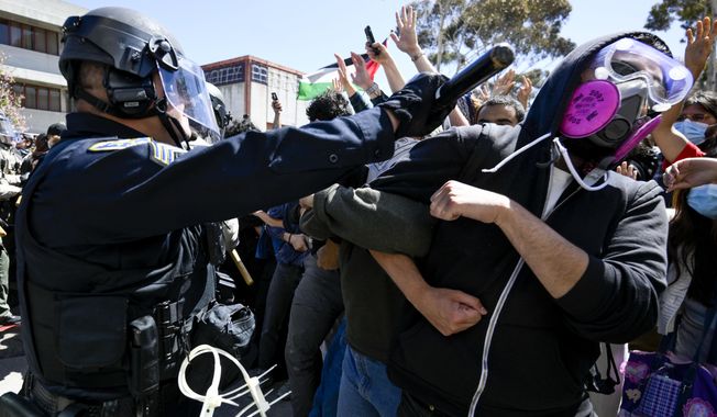 A protester is hit with a baton by a police officer at UC San Diego, May 6, 2024, in San Diego. As pro-Palestinian demonstrations escalate on college campuses around the country, critics of President Joe Biden’s handling of the Israel-Hamas war suggest this summer’s Democratic National Convention could be marred by protests and scenes of chaos that undermine his reelection. It raises the specter of a replay of 1968’s Democratic convention in Chicago, where a violent police crackdown created indelible scenes of chaos. (AP Photo/Denis Poroy, File)