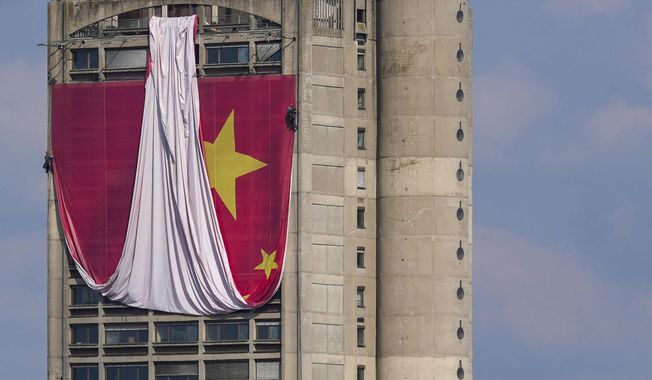 Workers hang on ropes to install a giant Chinese national flag on a skyscraper that is a symbolic gateway leading into the city from the airport, in Belgrade, Serbia, Saturday, May 4, 2024. Chinese leader Xi Jinping&#x27;s visit to European ally Serbia on Tuesday falls on a symbolic date: the 25th anniversary of the bombing of the Chinese Embassy in Belgrade during NATO&#x27;s air war over Kosovo. (AP Photo/Darko Vojinovic)