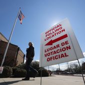 In this Feb. 26, 2020 file photo, using both the English and Spanish language, a sign points potential voters to an official polling location during early voting in Dallas, Texas. (AP Photo/LM Otero, File)