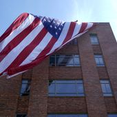 A giant American flag is unfurled on Lisner Hall on the campus of George Washington University in Washington, Friday, May 3, 2024, as demonstrators protest the Israel-Hamas war. (AP Photo/Susan Walsh)
