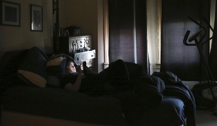 FILE - James Walter uses a phone at home in the Queens borough of New York, on April 7, 2021. Sleep scientists long ago established that insufficient sleep is linked with poor health outcomes, anxiety, obesity and several other negative effects. The research is equally conclusive that smartphones are particularly disruptive to the circadian clock that regulates sleep and other hormones. (AP Photo/Jessie Wardarski, File)