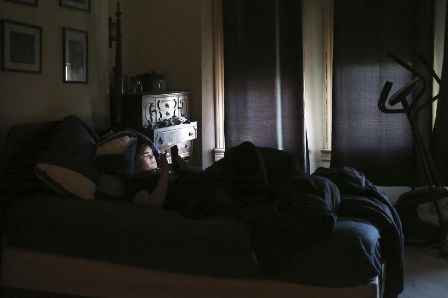 FILE - James Walter uses a phone at home in the Queens borough of New York, on April 7, 2021. Sleep scientists long ago established that insufficient sleep is linked with poor health outcomes, anxiety, obesity and several other negative effects. The research is equally conclusive that smartphones are particularly disruptive to the circadian clock that regulates sleep and other hormones. (AP Photo/Jessie Wardarski, File)