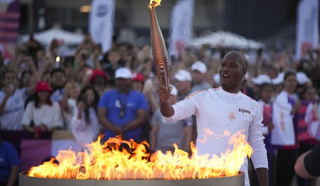 Torchbearer Didier Drogba of France holds the torch to light the cauldron at the Velodrome stadium in Marseille, southern France, Thursday, May 9, 2024. Torchbearers are to carry the Olympic flame through the streets of France&#x27;s southern port city of Marseille, one day after it arrived on a majestic three-mast ship for the welcoming ceremony. (AP Photo/Daniel Cole)