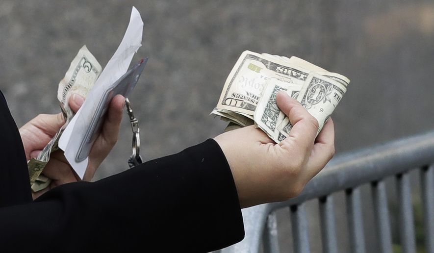 A woman pays with cash as she buys from a street vendor, Sept. 26, 2017 in New York. Despite numbers showing a healthy economy overall, lower-income spenders are showing the strain. (AP Photo/Mark Lennihan)