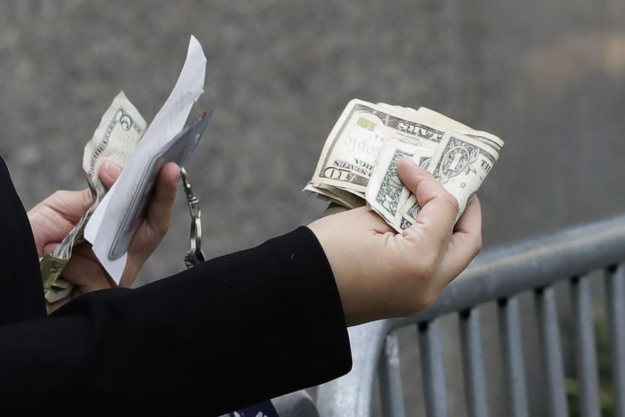 A woman pays with cash as she buys from a street vendor, Sept. 26, 2017 in New York. Despite numbers showing a healthy economy overall, lower-income spenders are showing the strain. (AP Photo/Mark Lennihan)