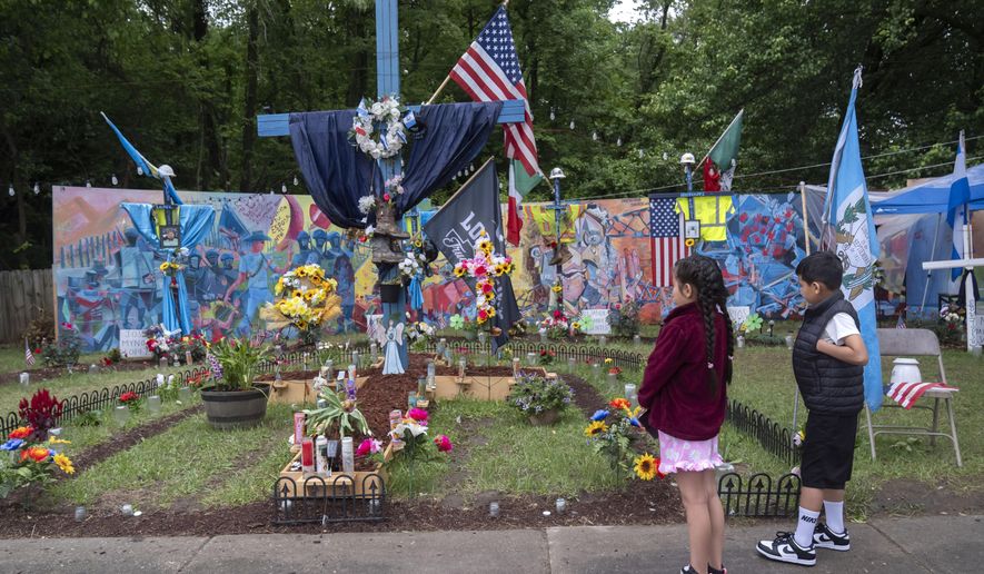 Visitors look at a memorial along a road leading to a park at the base of the collapsed Francis Scott Key Bridge, Sunday, May 12, 2024, in Baltimore. An effort to remove sections of the collapsed bridge resting on the container ship Dali was postponed on Sunday. (AP Photo/Mark Schiefelbein)
